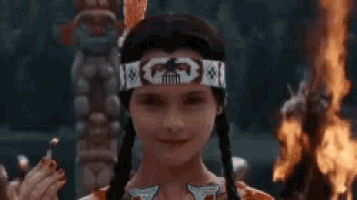 a little girl in a native american costume is holding a lighter in her hand .