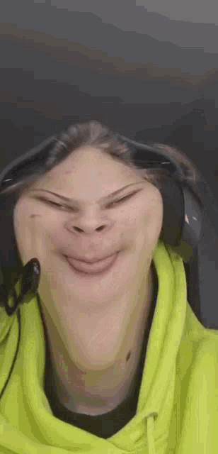 a person wearing a yellow hoodie and headphones is making a funny face .