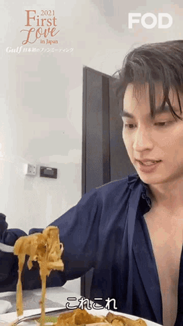 a man in a blue shirt is holding a plate of food with noodles coming out of it .