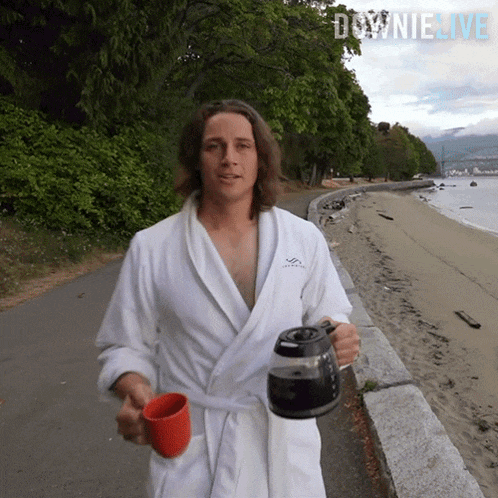 a man in a bathrobe is holding a coffee pot and a red cup