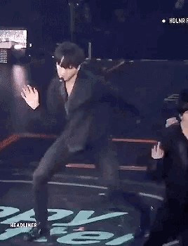 two men are dancing on a stage and one of them is holding the other 's leg .