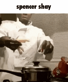 a man in a white chef 's coat is cooking food in a pot .