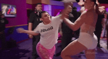 a woman wearing a zeus t-shirt is dancing with another woman .