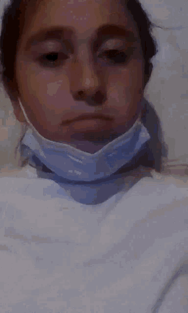 a woman wearing a face mask is laying in a bed .