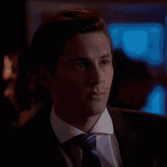 a man in a suit and tie is looking down at something .