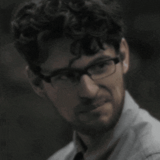 a close up of a man wearing glasses and a tie