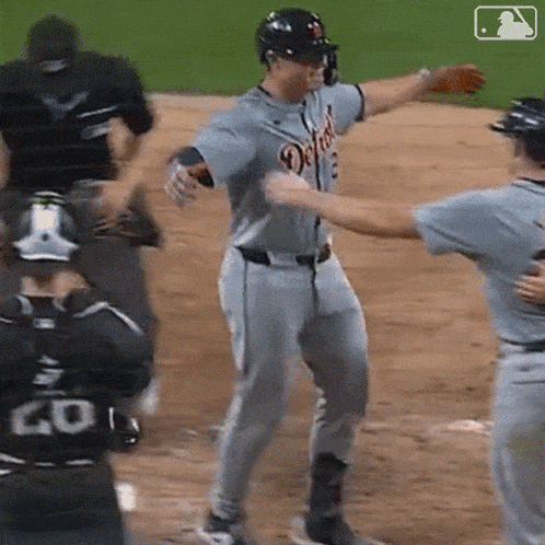 a baseball player wearing a detroit jersey is hugging another player on the field