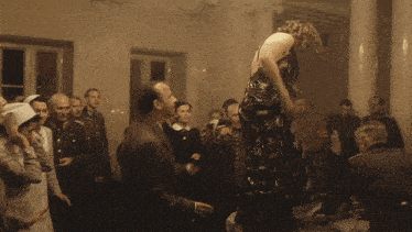a woman in a dress is dancing in front of a crowd of men