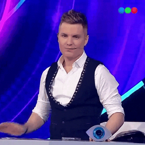 a man in a black vest and white shirt holds a trophy in front of a purple background