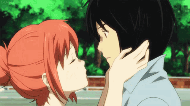a girl with red hair is kissing a boy with black hair .