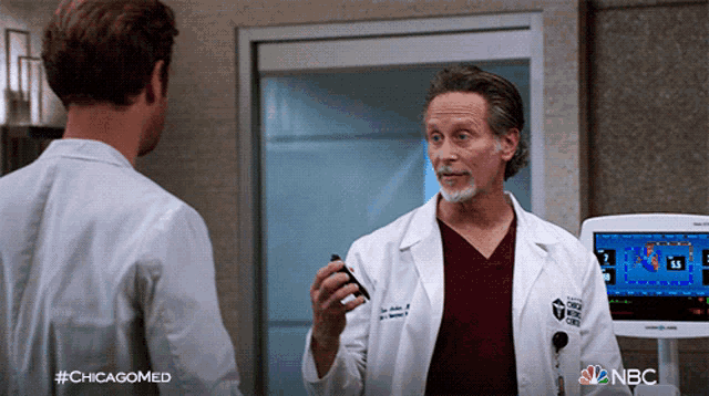 a man in a lab coat is talking to another man with #chicagomed written on the bottom