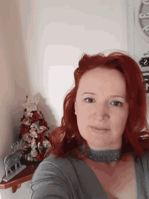 a woman with red hair takes a selfie in front of a christmas tree and a sign that says 2