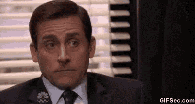michael scott is wearing a suit and tie and making a funny face .
