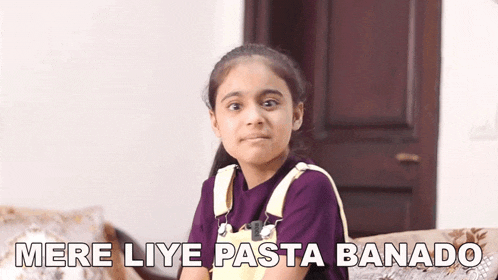 a young girl is sitting on a couch and making a face .
