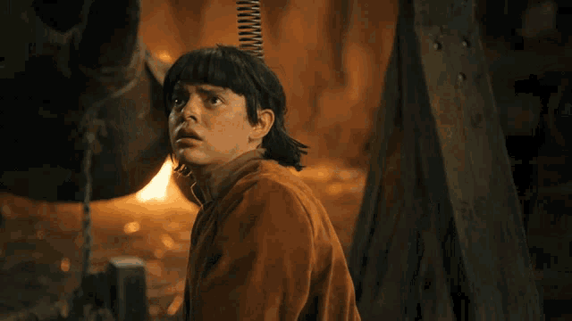 a woman in a blue shirt is holding a sword in her hand