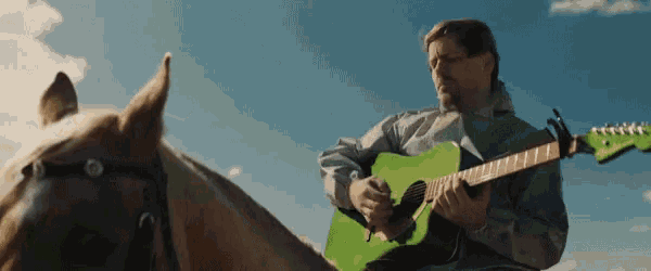 a man playing a green guitar while riding on the back of a horse