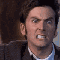 a close up of a man in a suit and tie making an angry face .