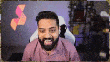 a man with a beard is sitting in a chair and smiling while talking on a video call .