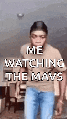a man is standing in a room and watching the mavs .