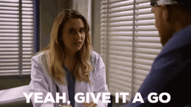 a woman in a lab coat is talking to a man in a hospital .
