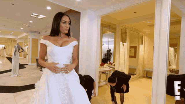 a woman in a wedding dress stands in a room