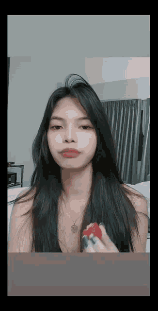 a young woman is holding a strawberry in her hand .