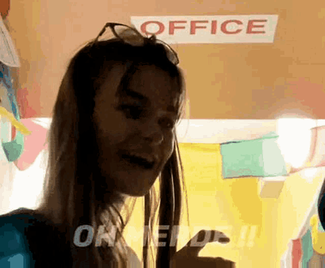 a woman stands in front of a sign that says office on it