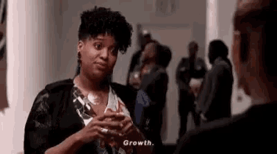 a woman is talking to another woman in a hallway while holding a glass of wine .