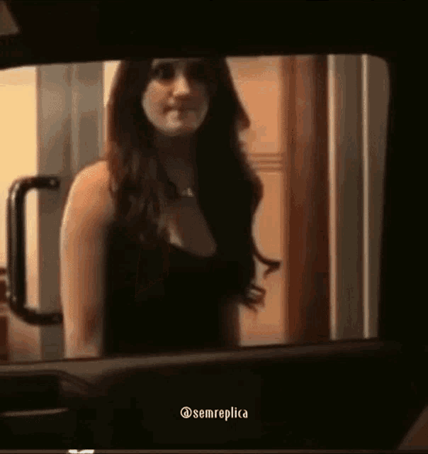 a woman in a black dress is standing in front of a door in a car .