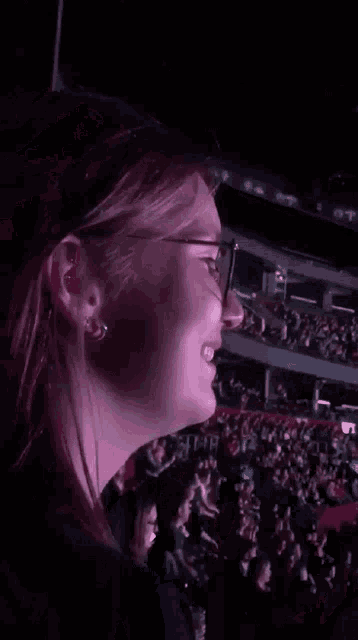 a woman covering her face with her hands in a crowded stadium .