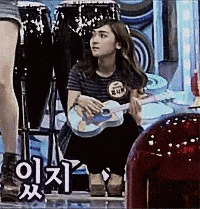 a woman is kneeling down while holding a guitar in her hands .