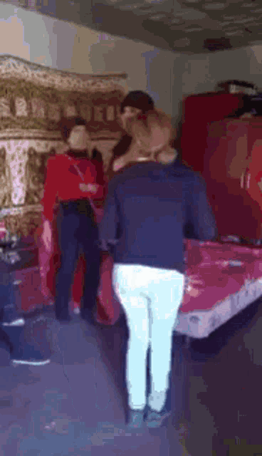 a group of people are standing around a bed in a room .