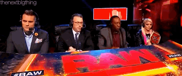 a group of people are sitting at a table in front of a raw sign .