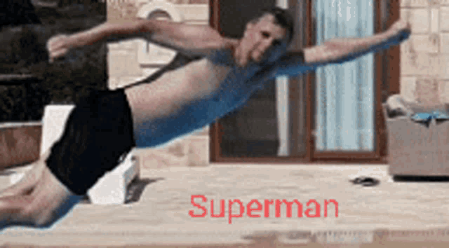 a shirtless man is doing a plank in front of a window and the word superman is on the bottom
