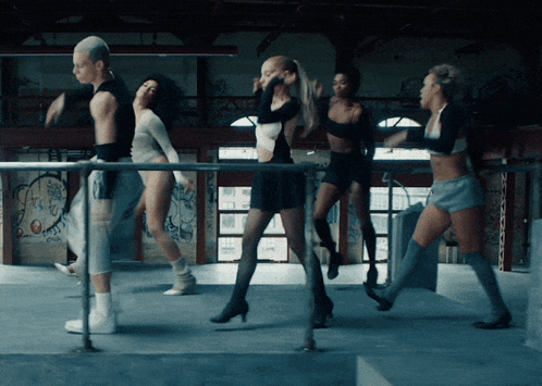 a group of female dancers are dancing in a room with graffiti on the wall