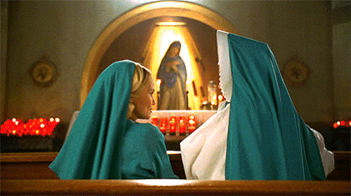 two nuns sit in front of a statue of mary