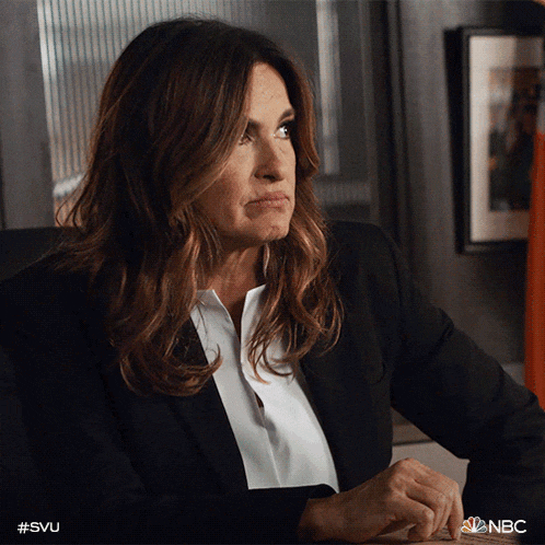 a woman in a suit and white shirt is sitting at a desk with nbc written on the bottom