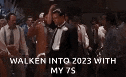 a man in a tuxedo is dancing in front of a crowd of men .