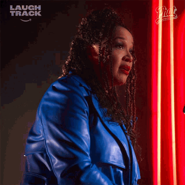 a woman in a blue jacket says good in front of a neon sign