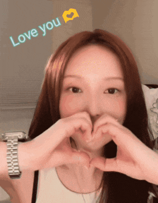a woman is making a heart shape with her hands and the words love you are above her