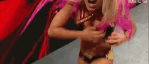 a woman in a bikini is standing on a stage holding her chest .