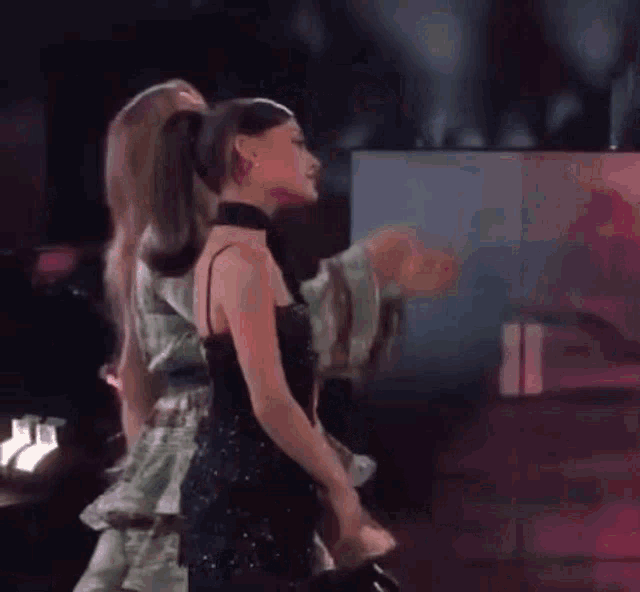 two women are standing next to each other on a stage and hugging each other .