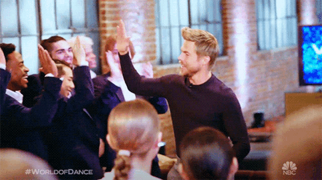 a group of people giving each other a high five with the words world of dance on the bottom right