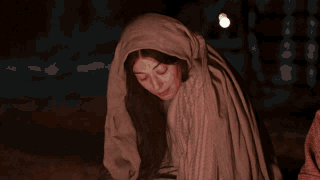 a woman with a hood on her head looks down at something