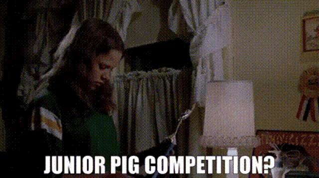 a girl in a green shirt is holding a trophy and the words junior pig competition are above her .