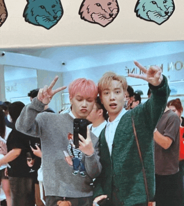 a man in a green cardigan is taking a picture of another man in a gray sweater