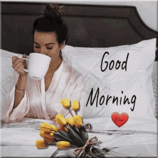 a woman drinking a cup of coffee on a bed with a good morning pillow