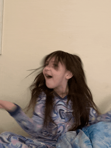 a little girl in a purple swirl pajama is making a face