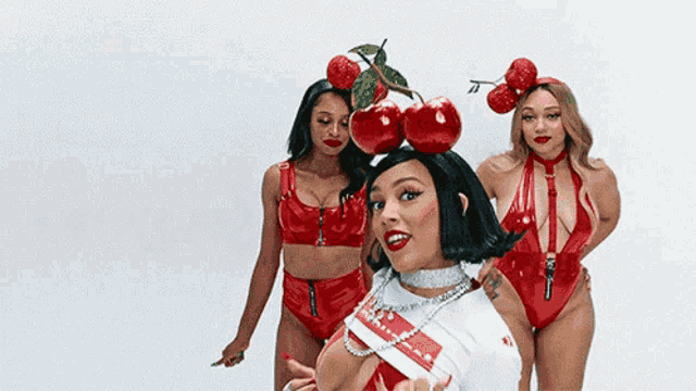 three women in red bikinis are standing next to each other with cherry hats on their heads .