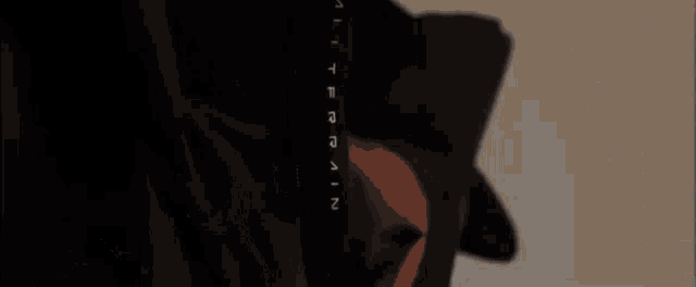 a man wearing a black jacket with a hood is standing in front of a wall with arrows pointing in different directions .